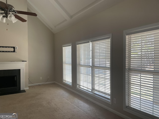 unfurnished living room featuring a wealth of natural light, light carpet, a fireplace with flush hearth, and vaulted ceiling with beams