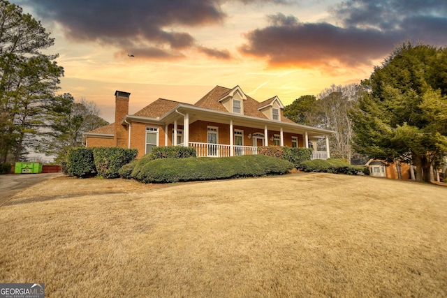 cape cod house featuring a front yard and covered porch