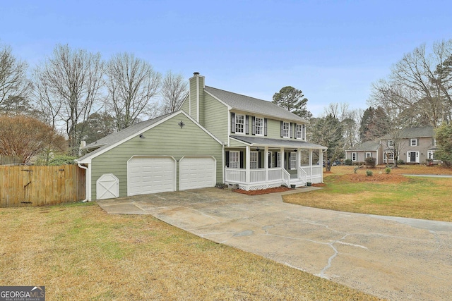 view of front of house featuring fence, a chimney, driveway, a front lawn, and a porch