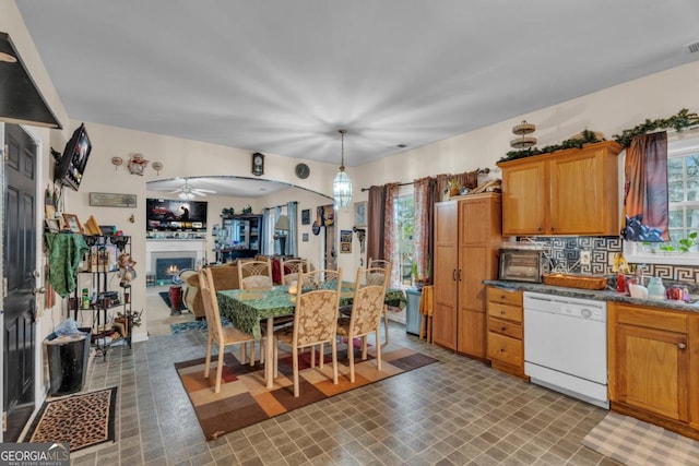 kitchen with plenty of natural light, dark countertops, dishwasher, and hanging light fixtures