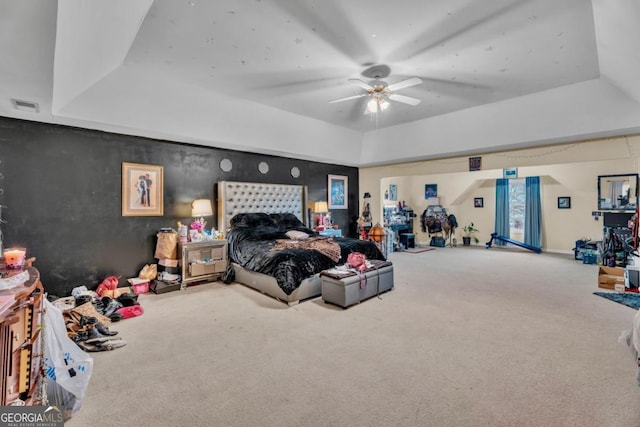 carpeted bedroom with visible vents, a raised ceiling, and a ceiling fan