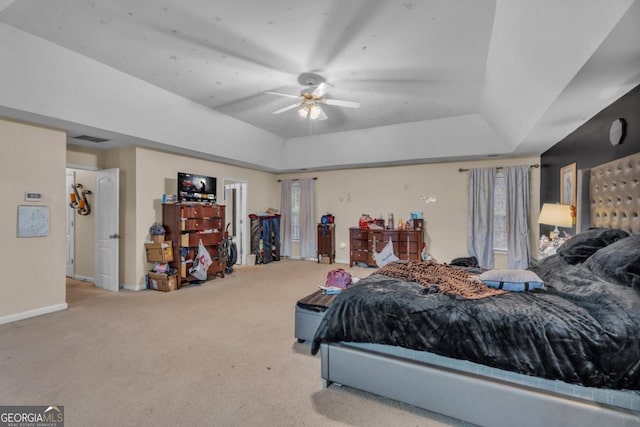 carpeted bedroom with a ceiling fan, a raised ceiling, visible vents, and baseboards