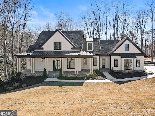 back of house featuring covered porch, roof with shingles, and a standing seam roof