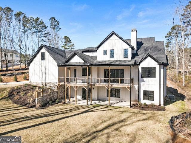 back of property featuring a yard, a shingled roof, a chimney, and a patio