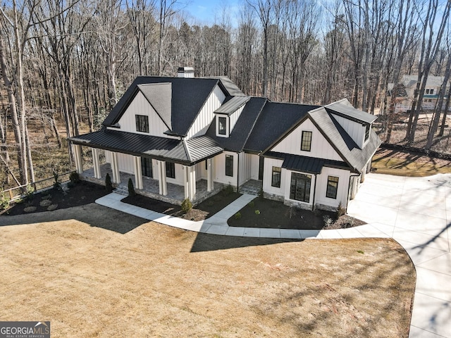 modern inspired farmhouse featuring a standing seam roof, metal roof, concrete driveway, and a front yard