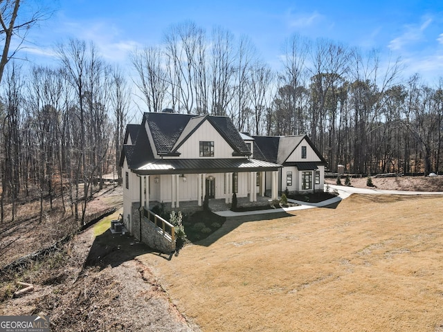 back of property with metal roof, a porch, a lawn, board and batten siding, and a standing seam roof