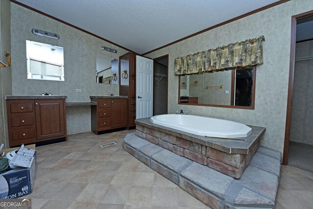 full bath featuring two vanities, a bath, a textured ceiling, visible vents, and ornamental molding