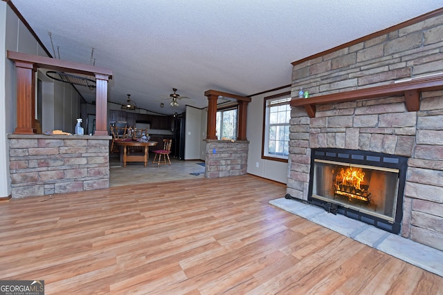 unfurnished living room featuring a ceiling fan, a textured ceiling, crown molding, wood finished floors, and a fireplace