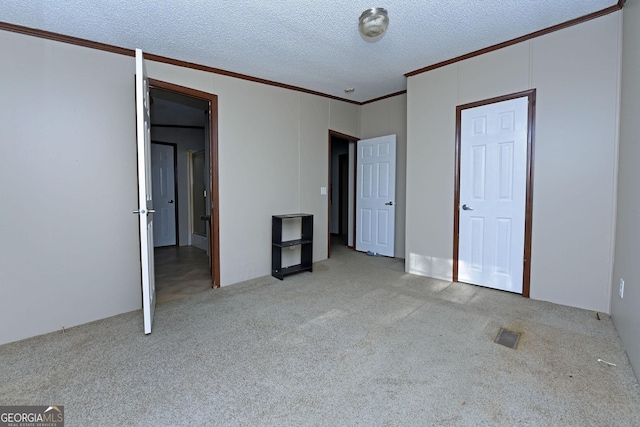unfurnished bedroom with a textured ceiling, crown molding, and carpet floors