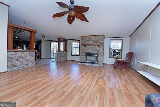 unfurnished living room featuring wood finished floors, a ceiling fan, crown molding, a textured ceiling, and a stone fireplace