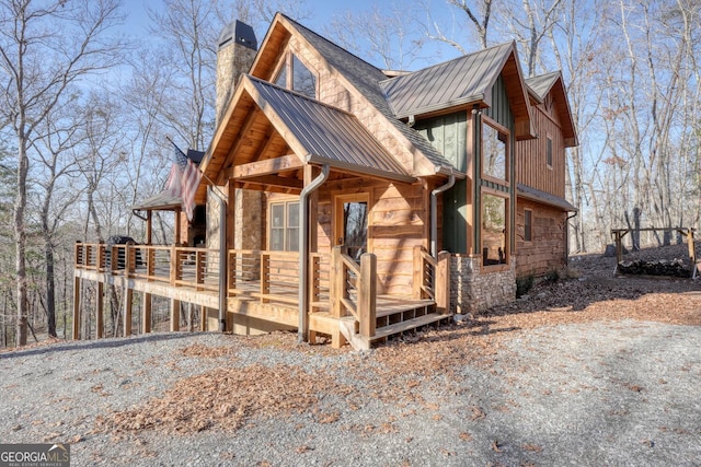 view of home's exterior featuring metal roof, a chimney, and stone siding