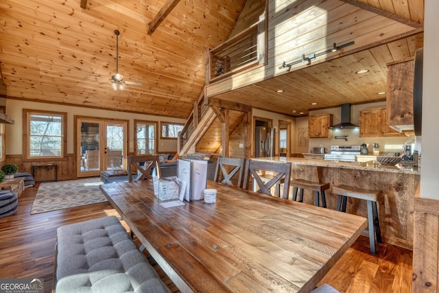 dining area with a wainscoted wall, high vaulted ceiling, wood ceiling, and wood finished floors