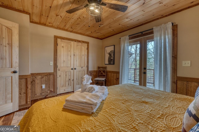 bedroom featuring a wainscoted wall, access to outside, french doors, and wood ceiling