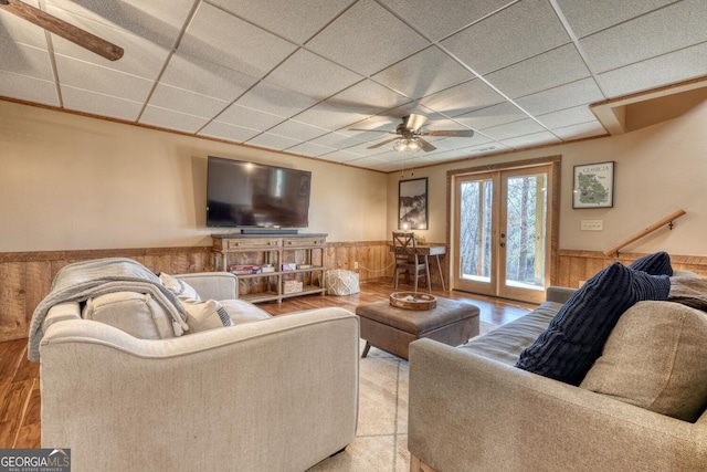 living area with french doors, wainscoting, a paneled ceiling, and wooden walls