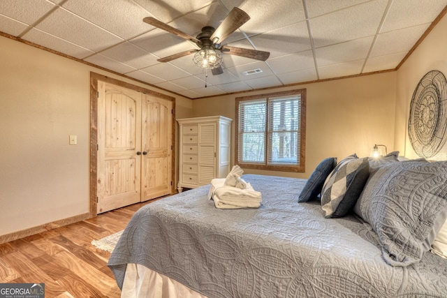 bedroom with baseboards, visible vents, ornamental molding, a paneled ceiling, and light wood-style floors