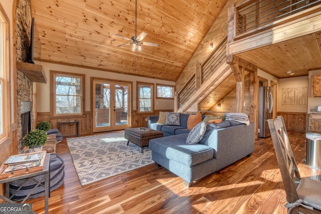 living room featuring french doors, stairway, wood walls, wooden ceiling, and wainscoting