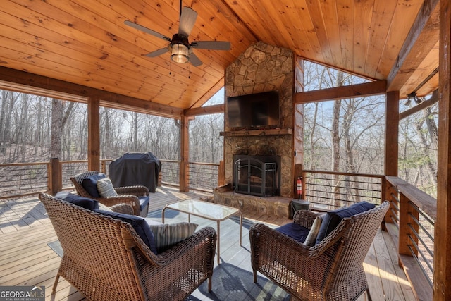 sunroom with lofted ceiling, an outdoor stone fireplace, wooden ceiling, and a ceiling fan