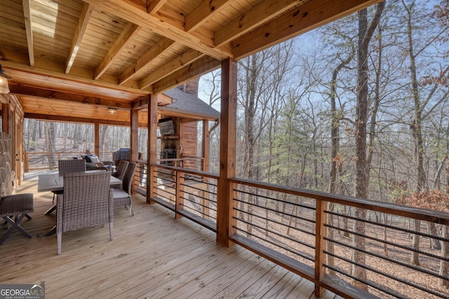 wooden terrace with outdoor dining space and a fireplace