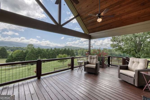 deck with a ceiling fan, a mountain view, and an outdoor living space