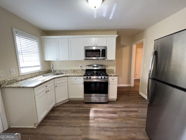 kitchen with white cabinets, light stone counters, stainless steel appliances, and a sink