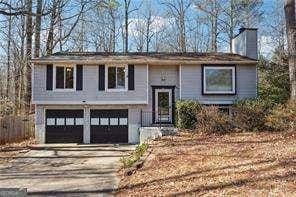 raised ranch with a chimney, driveway, and a garage