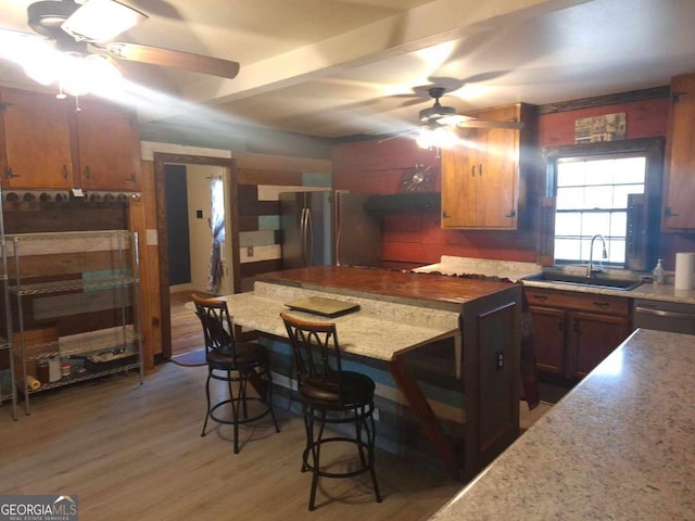 kitchen featuring a ceiling fan, appliances with stainless steel finishes, wood finished floors, light countertops, and a sink