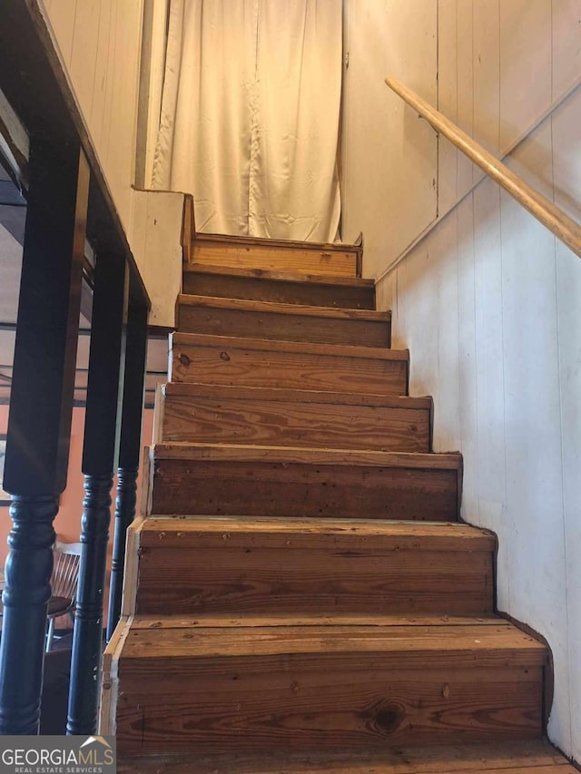 staircase featuring wood walls