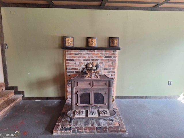 living area featuring a wood stove, concrete floors, baseboards, and stairs