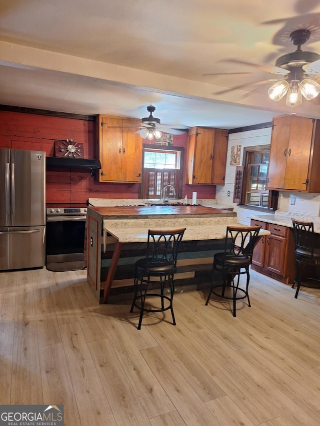 kitchen featuring brown cabinets, a ceiling fan, appliances with stainless steel finishes, and light wood-style floors