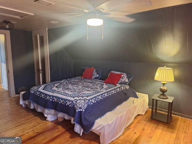 bedroom featuring visible vents, attic access, a ceiling fan, vaulted ceiling, and wood finished floors