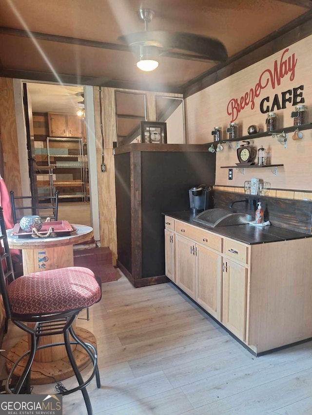 bar featuring light wood-style floors and a sink