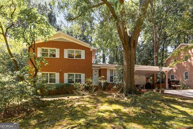 view of front facade with a front lawn, an attached carport, concrete driveway, and brick siding