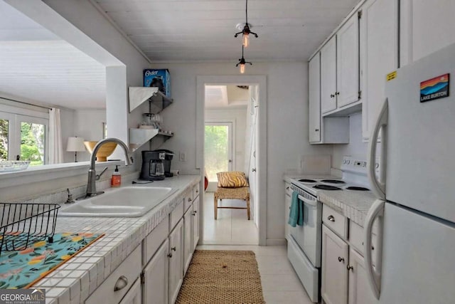 kitchen with tile countertops, light tile patterned floors, white cabinets, a sink, and white appliances