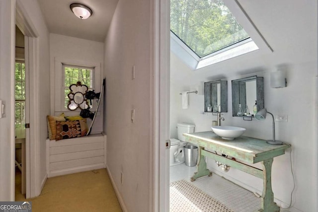 interior space featuring a skylight, a sink, and baseboards