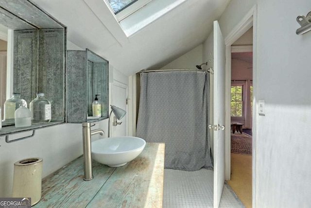 full bath featuring lofted ceiling with skylight, a sink, and a shower with shower curtain