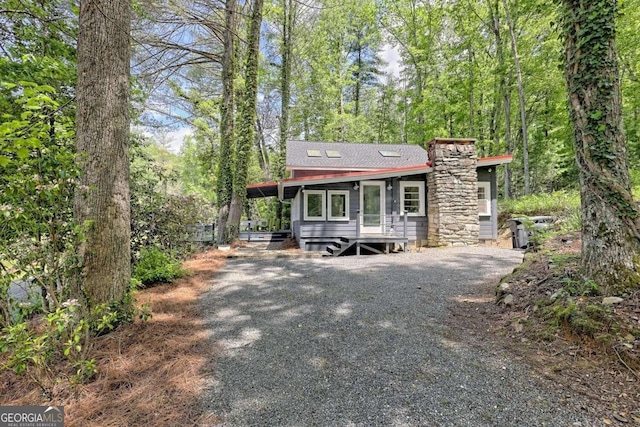 view of front of home with driveway, a chimney, and a carport