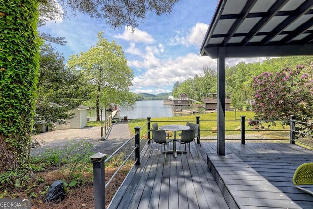 deck with outdoor dining space and a water view