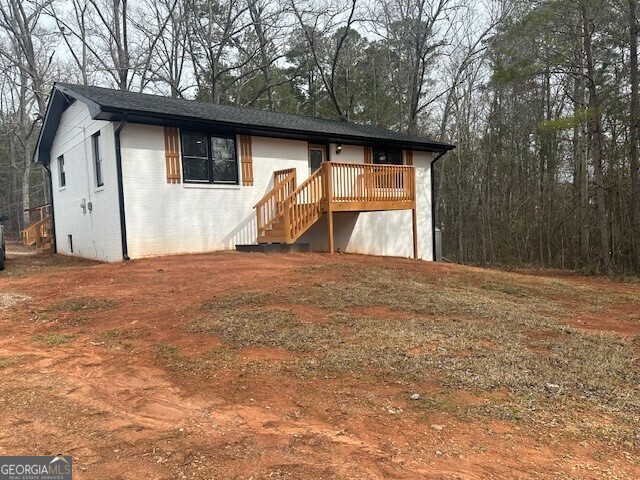 ranch-style home with brick siding, stairway, and a wooden deck