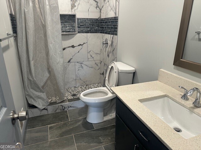 full bath with a stall shower, vanity, and toilet