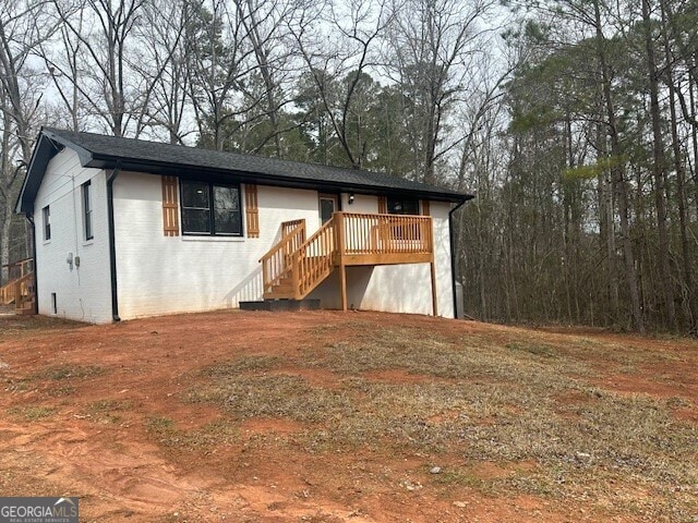 ranch-style house with a deck, brick siding, and stairway