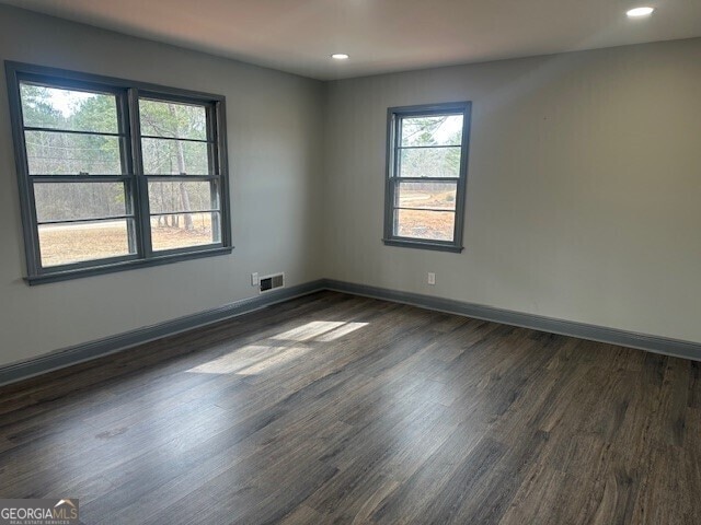 spare room with dark wood-type flooring, recessed lighting, visible vents, and baseboards