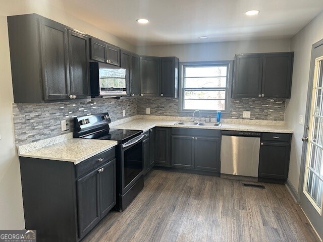 kitchen featuring stainless steel appliances, dark wood finished floors, light countertops, and a sink