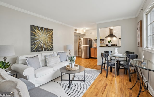 living area featuring light wood finished floors, visible vents, and crown molding