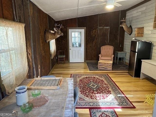 entrance foyer featuring wood walls, vaulted ceiling, and light wood-style floors