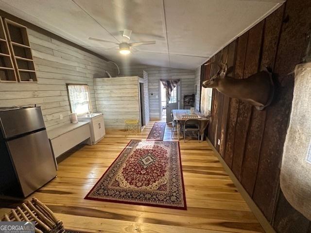 interior space with vaulted ceiling, light wood finished floors, and wooden walls