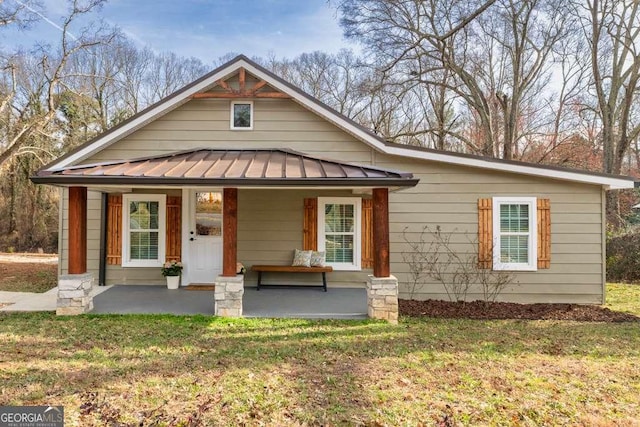 view of front of house with covered porch, a front yard, metal roof, and a standing seam roof