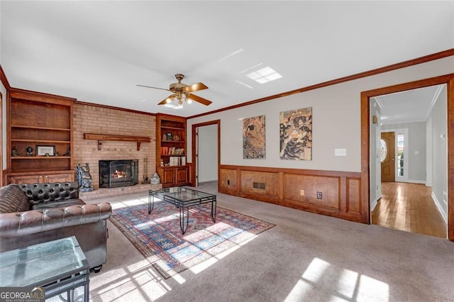 living room with a brick fireplace, built in features, crown molding, and light colored carpet