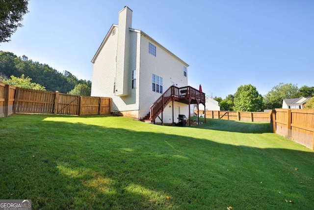 rear view of house with a deck, a fenced backyard, a lawn, and stairway