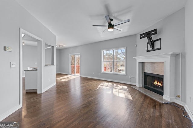 unfurnished living room with dark wood-style floors, a lit fireplace, and a ceiling fan