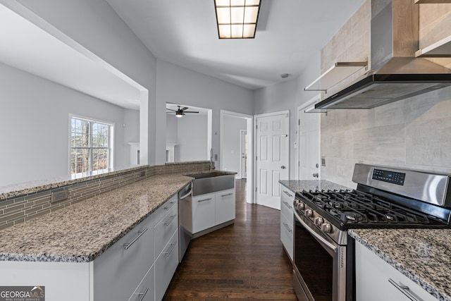 kitchen featuring appliances with stainless steel finishes, a sink, wall chimney exhaust hood, and light stone countertops